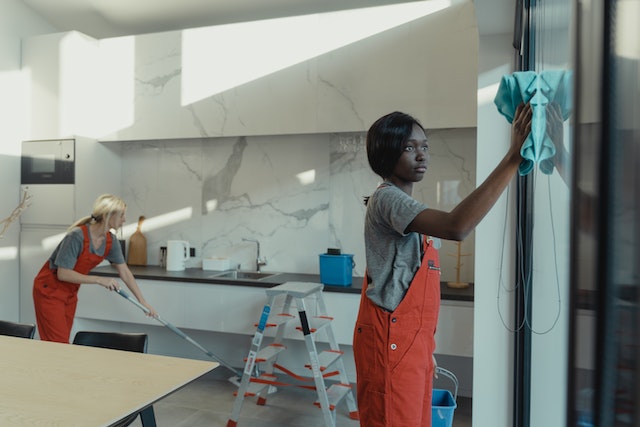 Two young people professionally cleaning the inside of a home.